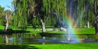 Decorative fountain, trees and shining rainbow on the golf course
